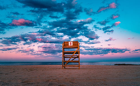 brown lifeguard chair facing the ocean under the gray clouds thumbnail