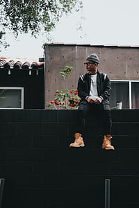 man sitting on top of gray concrete brick wall at daytime thumbnail