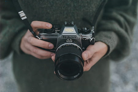 person holding black and gray Nikon MILC camera thumbnail