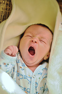 baby wearing onesie yawning with blanket thumbnail