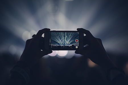 person holding smartphone with two hands filming a concert thumbnail