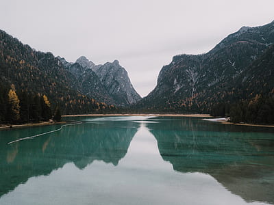 body of water surrounded by mountains and trees thumbnail
