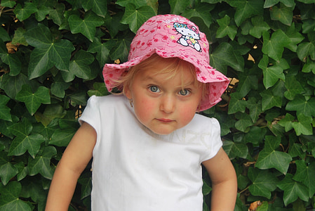 girl wearing pink bucket hat beside plants thumbnail