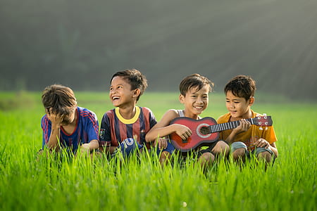 four boys sitting on green grass thumbnail
