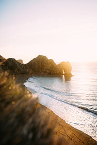 arch rock formation near body of water thumbnail