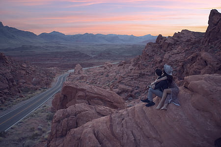 couple hugging each other on top of the rock formation thumbnail