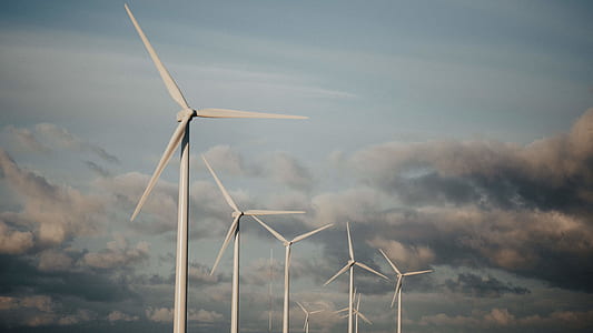 white wind turbines under gray clouds and blue sky during daytime thumbnail