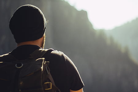 man in black t-shirt, black beanie, and brown backpack thumbnail