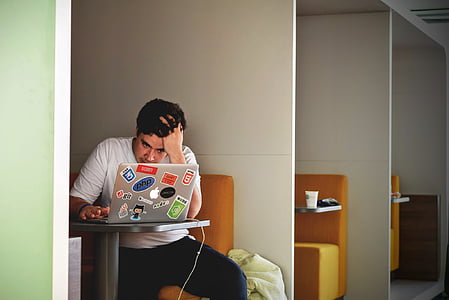man sitting in front of table while using silver MacBook thumbnail