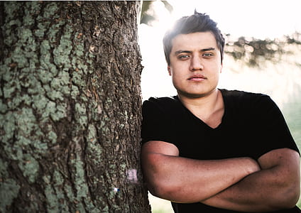 man leaning beside tree thumbnail