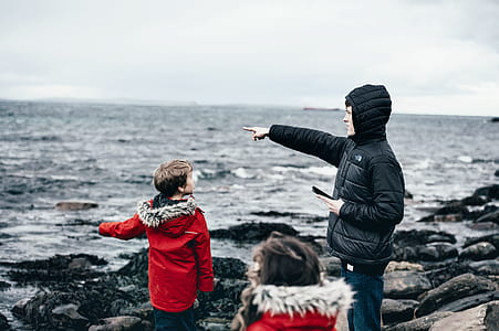 man wearing hoodie pointing at sea in front of child wearing red jacket thumbnail