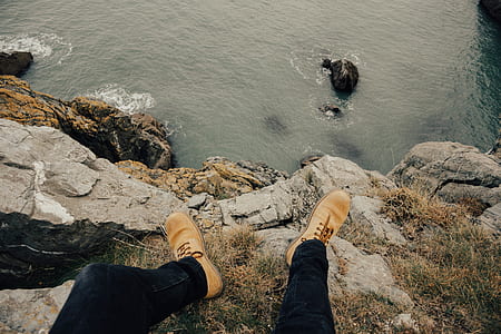 man standing on mountain cliff near body of water thumbnail