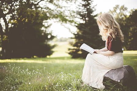 girl reading book as she sits on a rock thumbnail