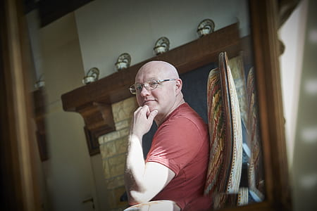 man sitting on chair near fireplace panel thumbnail