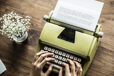 person typing on typewriter on brown surface thumbnail