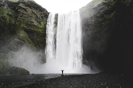 person standing in front of waterfalls thumbnail