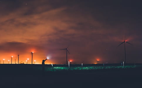 Photography of Person Holding Flashlight Near Windmills during Night Time thumbnail