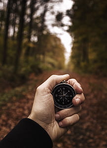 person holding round gray compass thumbnail