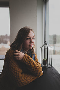 woman leaning on black wooden desk near lamp and window during daytime thumbnail