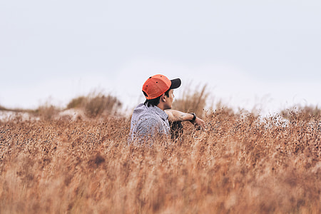 man sitting alone on brown grass field thumbnail