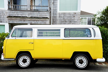 yellow and white Volkswagen Type 2 van parked in front of gray house thumbnail