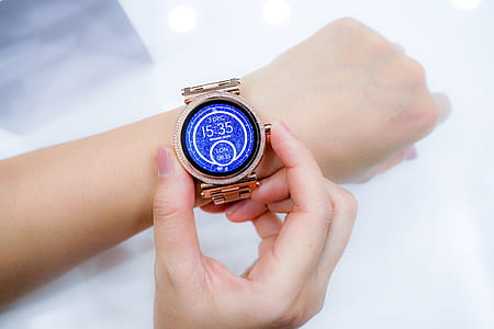 person holding gold-colored smartwatch on her left wrist thumbnail