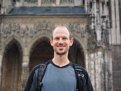 bokeh photography of man standing in front of gray building thumbnail