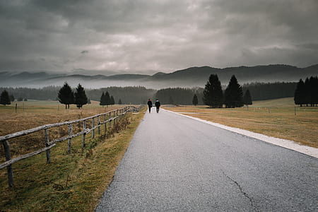 person walking on asphalt road towards to mountain thumbnail