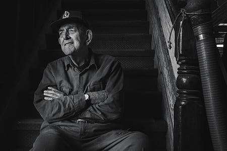 grayscale photography of man sitting on stairs with cross arms thumbnail