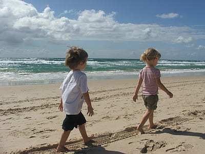 two toddlers walking on seashore thumbnail