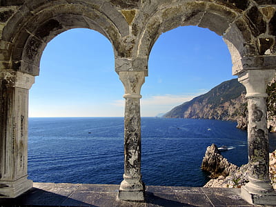 arch-shaped gray concrete pillar beside the sea thumbnail