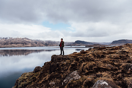 man standing on cliff edge during daytime thumbnail