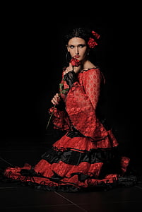 woman wearing red and black long-sleeved ruffled dress holding rose on black background thumbnail
