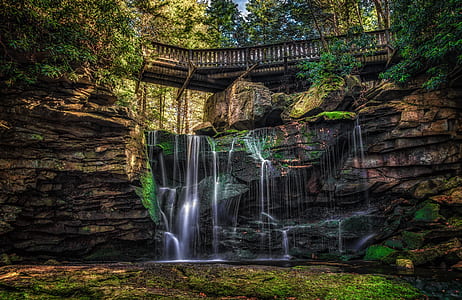 time-lapse of waterfall under brown wooden bridge taken at daytime thumbnail