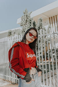 woman standing while wearing jacket and eyeglasses besides metal fence thumbnail