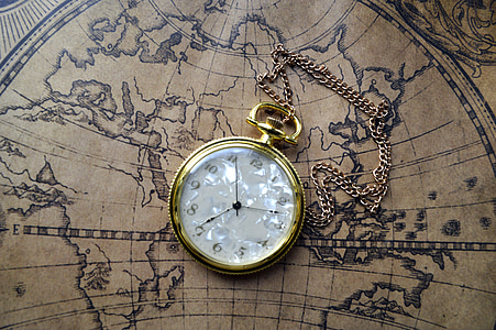 round gold-colored framed analog pocket watch on brown map thumbnail