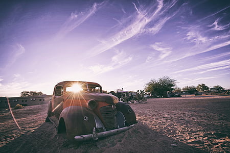 brown classic car without tires parked on sandy area under white and blue cloudy sky during daytime thumbnail