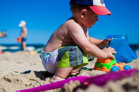 boy playing toy on white sand thumbnail
