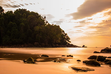 silhouette of mountain beside shore during golden hour thumbnail