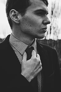 man in black suit jacket holding his necktie thumbnail