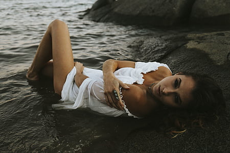 woman lying on rock near water thumbnail
