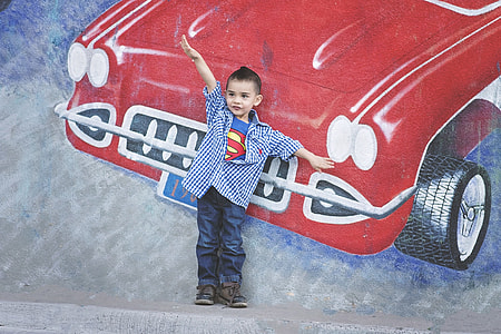 boy standing beside red vehicle wall graffiti with hands on air thumbnail