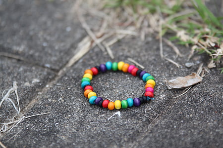 selective focus photo of beaded multicolored bracelet on gray concrete pavement thumbnail