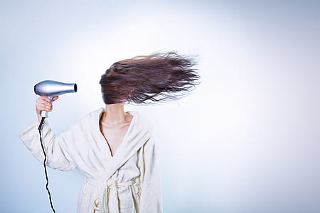 woman holding hair blower performing to dry her hair thumbnail