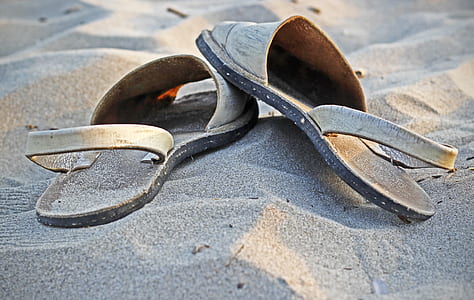 pair of brown-and-black slingback sandals on beach sand thumbnail
