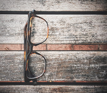 black and brown framed eyeglasses on gray and brown wooden surface thumbnail