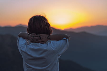 woman standing on mountain watching sunset thumbnail