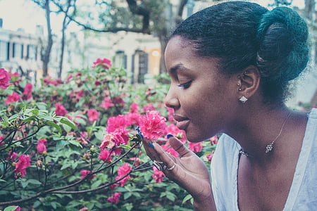 woman in gray scoop neck shirt smelling pink flowers thumbnail