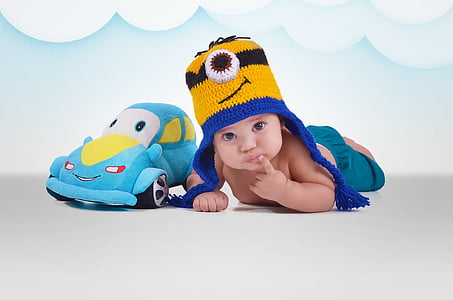baby lying beside blue car plush toy thumbnail