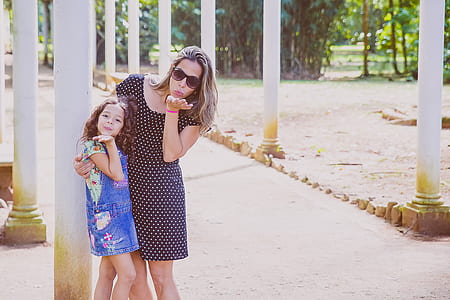 woman and girl blowing kisses outdoor during daytime thumbnail